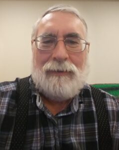 Elderly man with glasses and white beard.